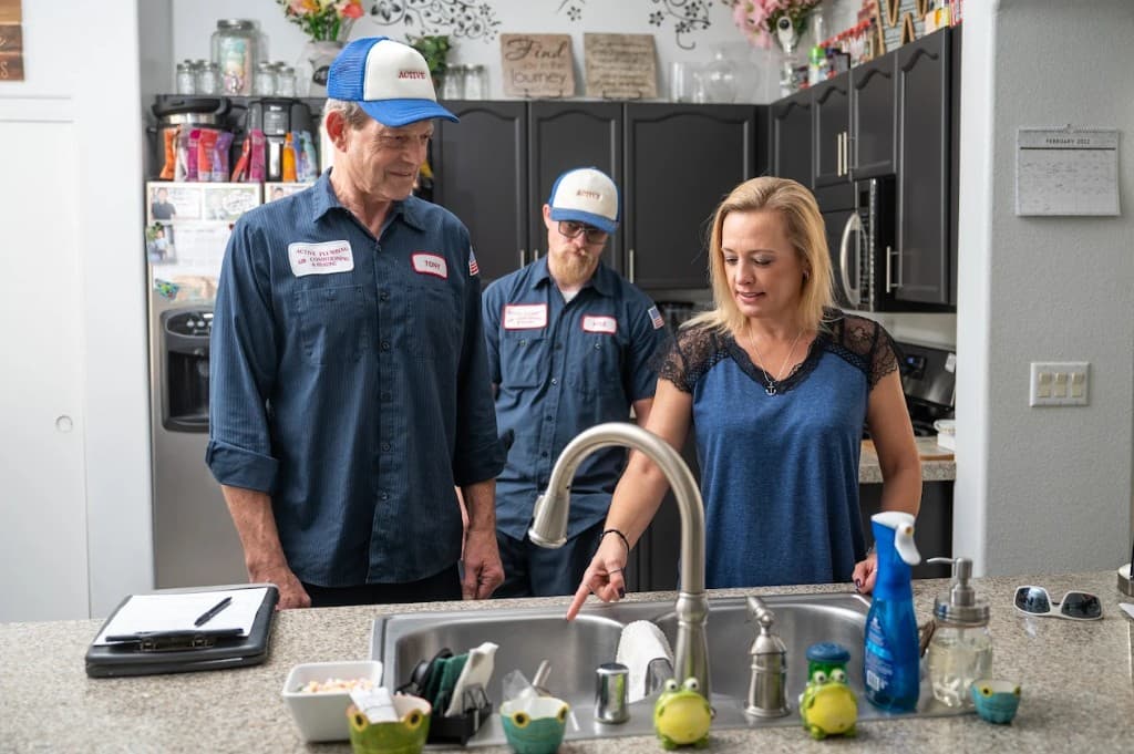Drain Cleaning - Drain & Sewer Services in Las Vegas | Active Plumbing. Active Plumbing technicians consulting with a homeowner at a kitchen sink during a service visit.